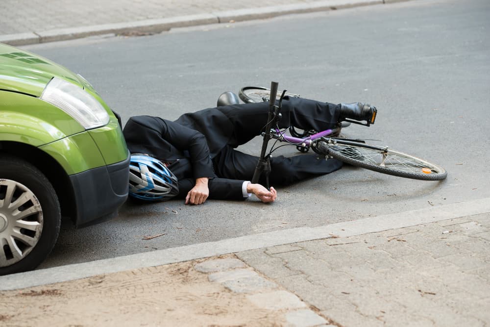 Unconscious male cyclist lying on the road after a traffic accident.